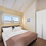 Schlafzimmer mit Doppelbett, Fenster, Kleiderschrank und Wandbild.