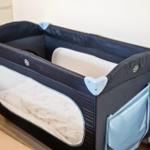 Ein tragbarer Kinderbett mit Rollen und einem Gitterfenster.