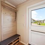 Eingangsbereich mit Holzgarderobe, Sitzbank und Tür zum Garten.
