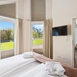 Schlafzimmer mit Blick auf Garten, TV und Zugang zum Wohnbereich.