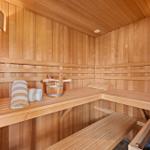 Sauna mit Holzbänken, Handtuch und Eimer. Holzwand und -decke.