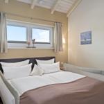 Schlafzimmer mit Doppelbett, Fenster und Wandbild.