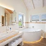 Badezimmer mit Badewanne, Waschbecken und Toilette unter Holzdecke.
