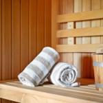Sauna mit Holzbank, gefalteten Handtüchern und Eimer mit Kelle.