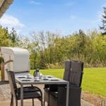 Terrasse mit Tisch, Stühlen und Himmel. Im Hintergrund Gras und Bäume.