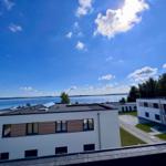 Modern building with view of a lake under blue sky with white clouds.