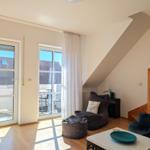 Living room with seating, glass doors, and wooden floor. Staircase on the right.