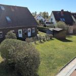 House with garden, terrace, and small sheds in the background.