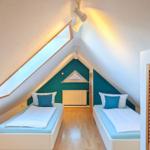 Two single beds under sloped ceilings with wooden floor and skylight.