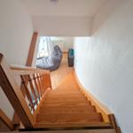 Wooden staircase leads to a room with a bean bag chair and window.