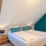 Bedroom with double bed, nightstand, and window under sloped ceiling.