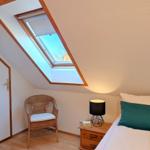 Bedroom with sloped ceiling, skylight, chair, and nightstand.