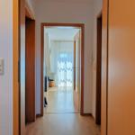 Hallway with wooden doors and light leading to the living area.