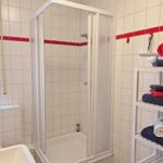 Bathroom with shower, window, and towel rack with towels.
