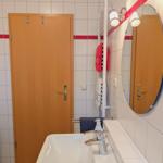 Bathroom with washing machine, mirror, and towel rack.