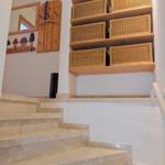 Staircase with stone steps and wooden shelves with baskets on the wall.
