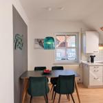 Dining area with table, chairs, and window. Kitchen with countertop and cabinets.