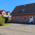 Red brick house with skylights and white doors. Front yard with lawn and hedge.