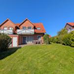 Red brick house with balcony and garden. Table and chairs are outside.