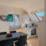 Dining area with table and chairs, kitchen with stove and skylight.