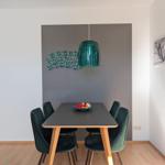 Dining area with table, chairs, and pendant light on gray wall