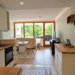 Küche mit Essbereich und Wohnzimmer mit Balkon und Holzboden.