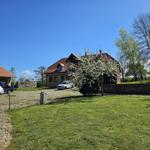 House with red roof, green lawn, and blue sky. Several cars parked in front of the building.