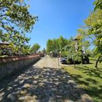 Stone wall and cobblestone path lead to entrance. Car parked on lawn.