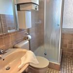 Badezimmer mit Dusche, Toilette und Waschbecken. Wand- und Bodenfliesen in Braun.