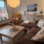 Ein Wohnzimmer mit braunem Sofa, Holztisch und Fensterblick auf die Landschaft.