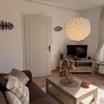 Wohnzimmer mit Sofa, TV, Tisch und Fenster. Wanddekoration und Hängelampe.