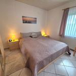 Schlafzimmer mit Doppelbett, Nachttischen und Fenster mit Vorhängen.