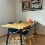 Holztisch mit vier Stühlen und Wickerlampe an der Wand