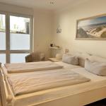 Schlafzimmer mit Doppelbett, Fenster und Strandbild an der Wand.