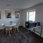 Raum mit runden Tisch, vier Stühlen und Küchenzeile mit Mikrowelle und Toaster.