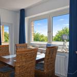 Esszimmer mit Tisch, Stühlen und Fensterblick auf Grün.
