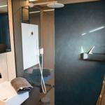 Dusche mit Glaswand, Waschbecken und Spiegel an Holzwand