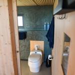 Badezimmer mit Toilette, Fenster und Holzwand