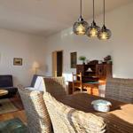 Dining area with table and chairs, living area with sofa and coffee table, kitchen area in background.