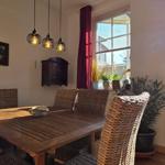 Dining room with wooden table, rattan chairs, and garden view through window.