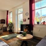 Living and dining area with sofa, table, chairs, and windows.