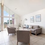 Living room with sofa, armchairs, and large window to terrace