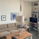 Living room with sofa, table, TV, and sea view.