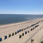 Beach with colorful beach chairs and promenade. View of the sea under blue sky.