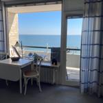 Room with sea view, table, chairs, and balcony with lounge chairs.