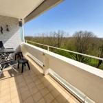 Terrace with table, chairs, and view of forest and sky.