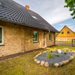 Ein Haus mit Backsteinfassade und Dachgauben. Vorgarten mit Steinbeet und Zaun.