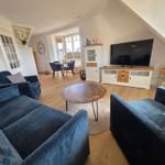 Wohnzimmer mit blauen Sofas, TV und Essbereich im Hintergrund.