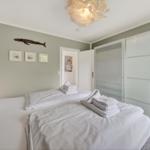 Schlafzimmer mit Doppelbett, weißen Bettwäsche und Glaswand-Schrank.