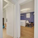 Schlafzimmer mit blauer Wand und weißem Bett. Nebenraum mit Toilette und Tür.